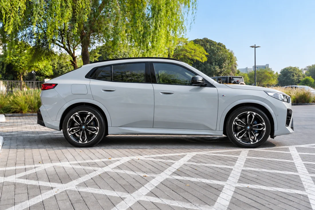 BMW X2 White — white side profile beside a tree-lined street