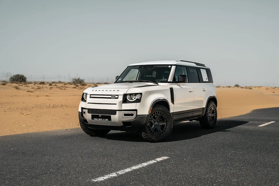 Land Rover Defender — white front three-quarter exterior on a paved desert road