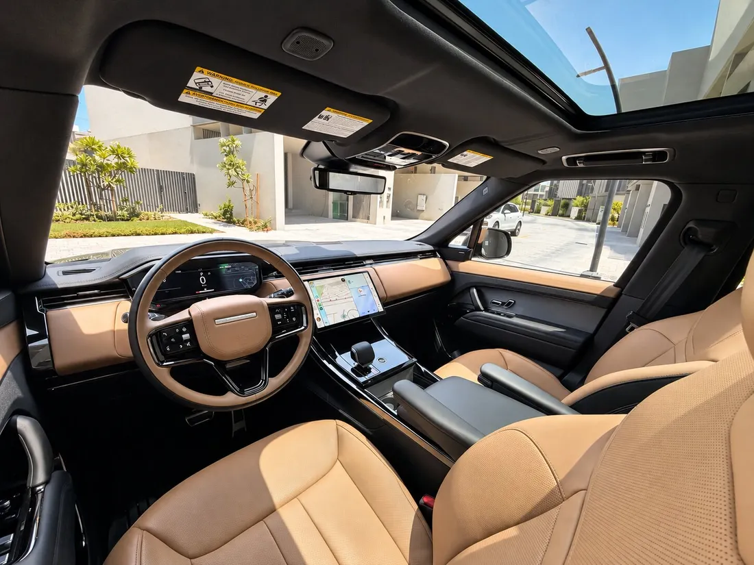 Range Rover Sport — tan front seats and dashboard beneath the glass roof
